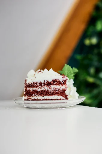 Porción de tarta red velvet con crema y hojas de menta