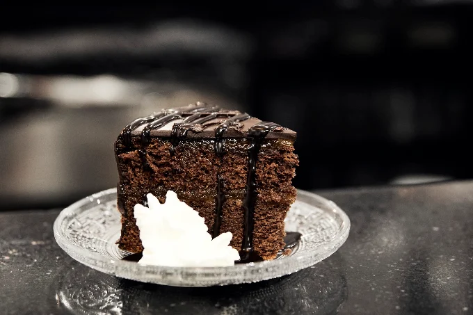 Porción de torta de chocolate con nata sobre la barra de mármol negro
