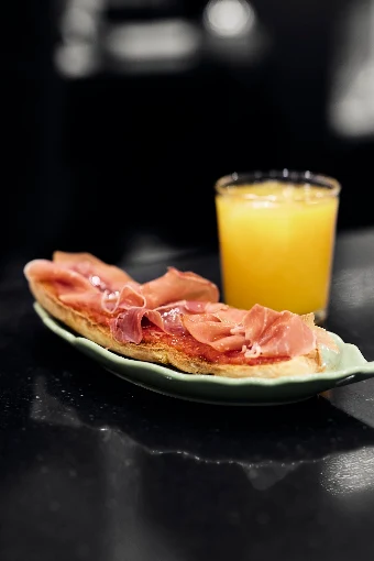 Tostada con tomate y jamón serrano junto a un zumo de naranja natural
